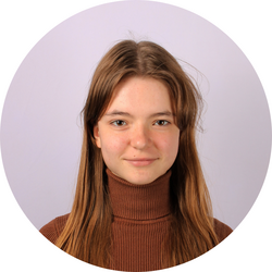 Close-up headshot of tutor Anna wearing a turtleneck and standing in front of a lavender wall.