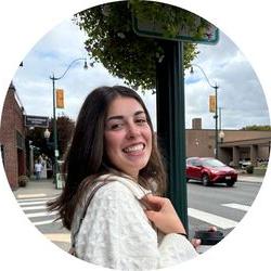 Photo of Alexandria wearing a white jacket and standing on a street corner.